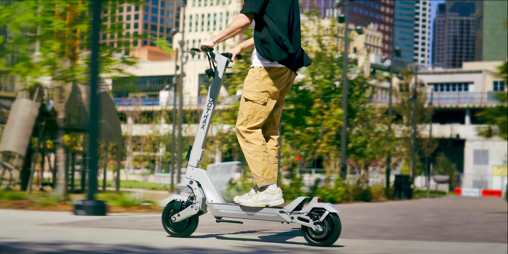 A man riding the GOTRAX GX2 foldable performance electric scooter with dual suspension and dual brakes.