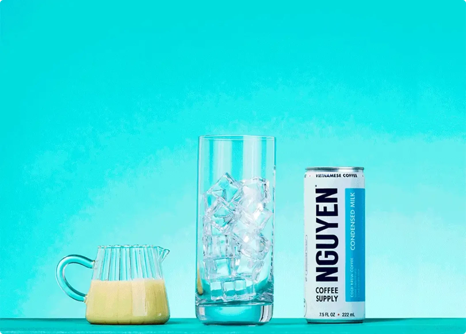 A can of Vietnamese coffee, a glass with ice, and a small pitcher on a turquoise background.