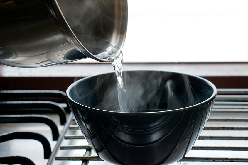 a pot of hot water being poured into a bowl