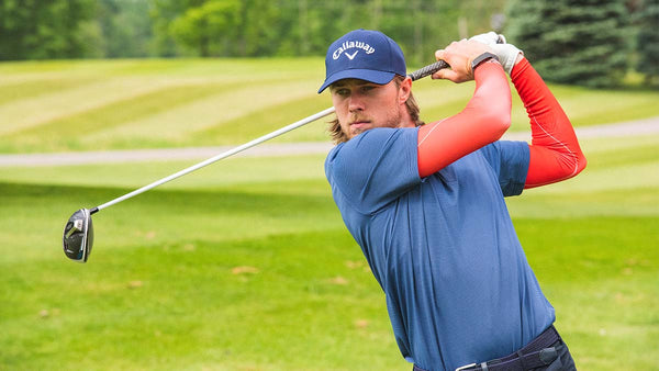 Golfer Adam Migur watches his ball soar after a swing, with the eSmartr POWER sleeve on his arms.