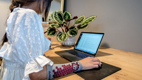 A woman monitors her emails wearing an eSmartr sleeve to reduce stress and increase concentration.