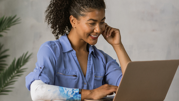 A woman works at a laptop with an eSmartr smart compression sleeve on her arm.