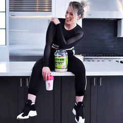 woman sitting on counter with bottle of Lean Whey shake in her hand