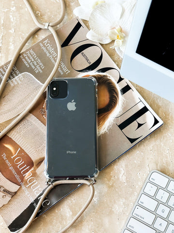 transparent iphone case with long beige strap on a magazine