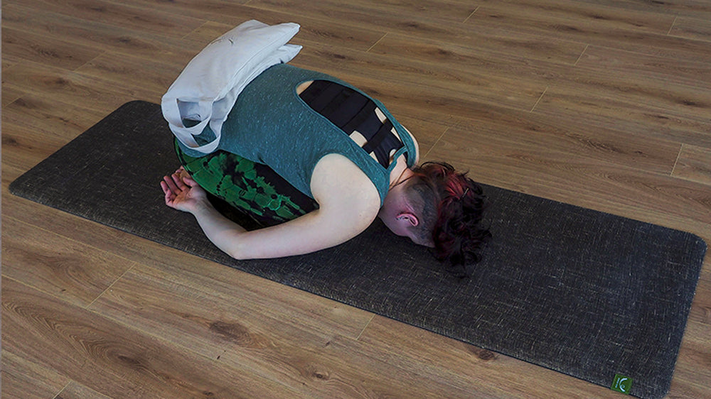 Balasana (postura del niño) con sacos de arena de yoga