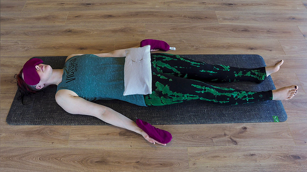 Savasana using eye pillows and yoga sandbag