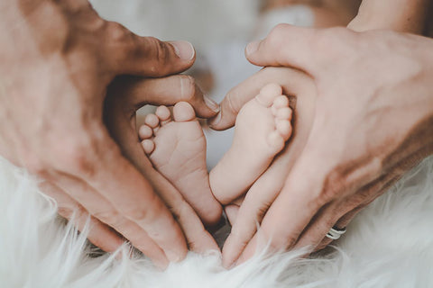 mom and dad's hands holding baby's feet in a heart shape