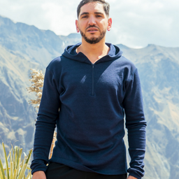 A man hiking outdoor wearing navy blue alpaca wool base layer hoodie