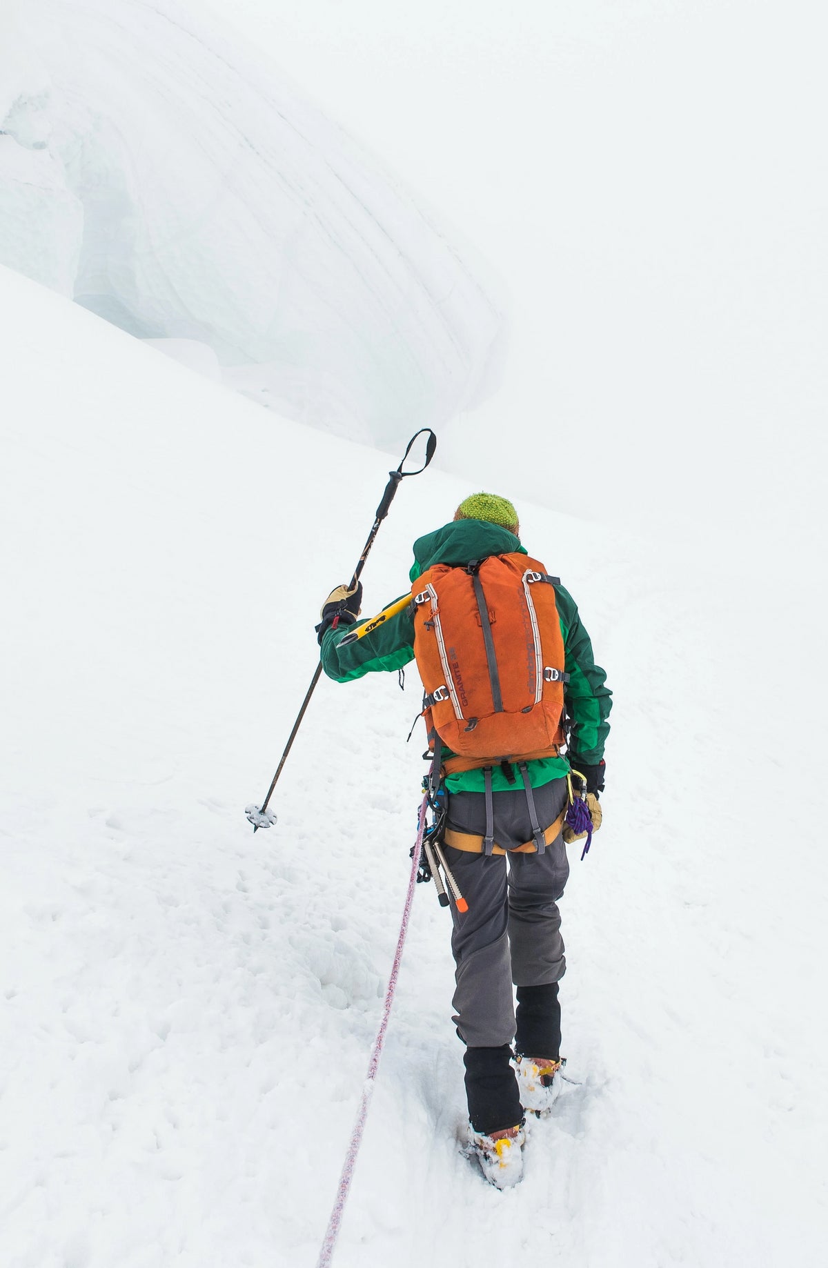 Man hiking outdoors in winter, walking through snow and using synthetic outdoor equipment