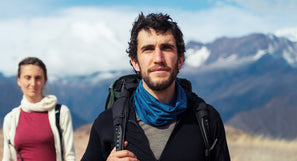 Man hiking outdoors in winter, walking through snow and using synthetic outdoor equipment