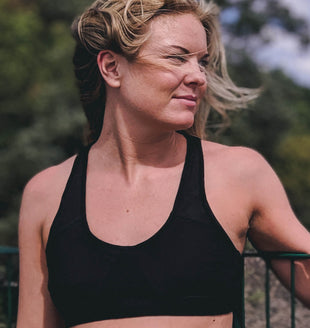 Woman wearing a black alpaca wool sportsbra, looking over her shoulder