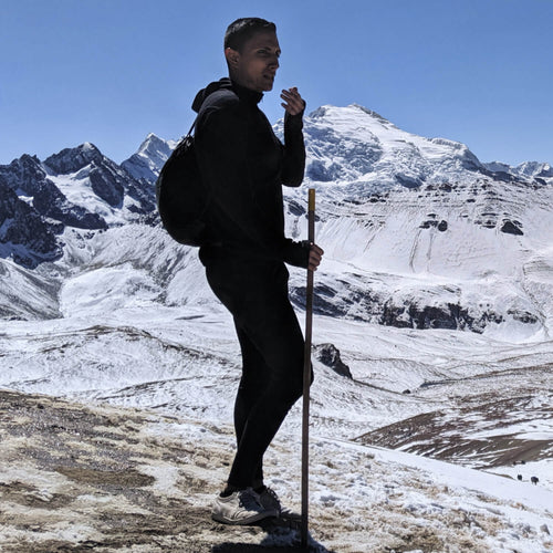 Man wearing alpaca wool base layer and wool hiking pants with a snowy mountain background