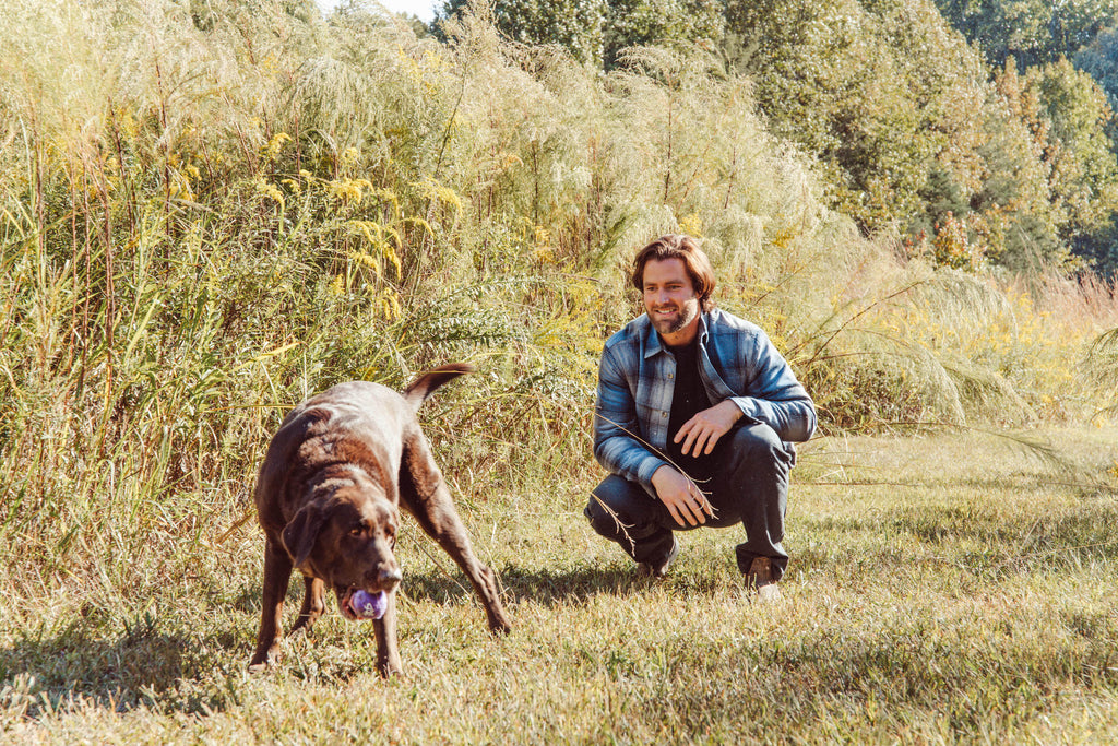 Man wearing flannel shirt playing with his dog