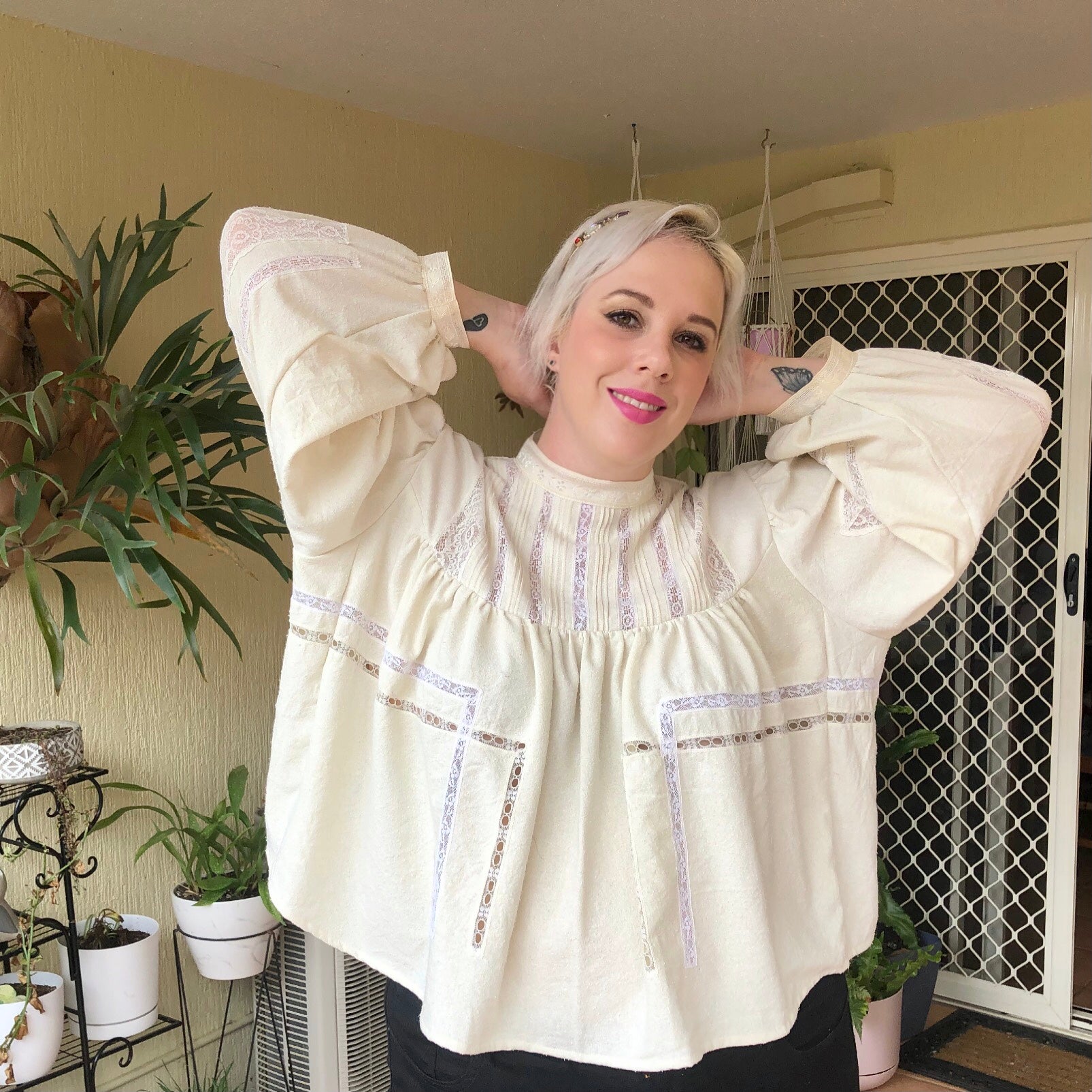 Shannon poses with her hands behind her head whilst smiling at the camera, showing the lace panel details across the front of her Gibson Girl Blouse
