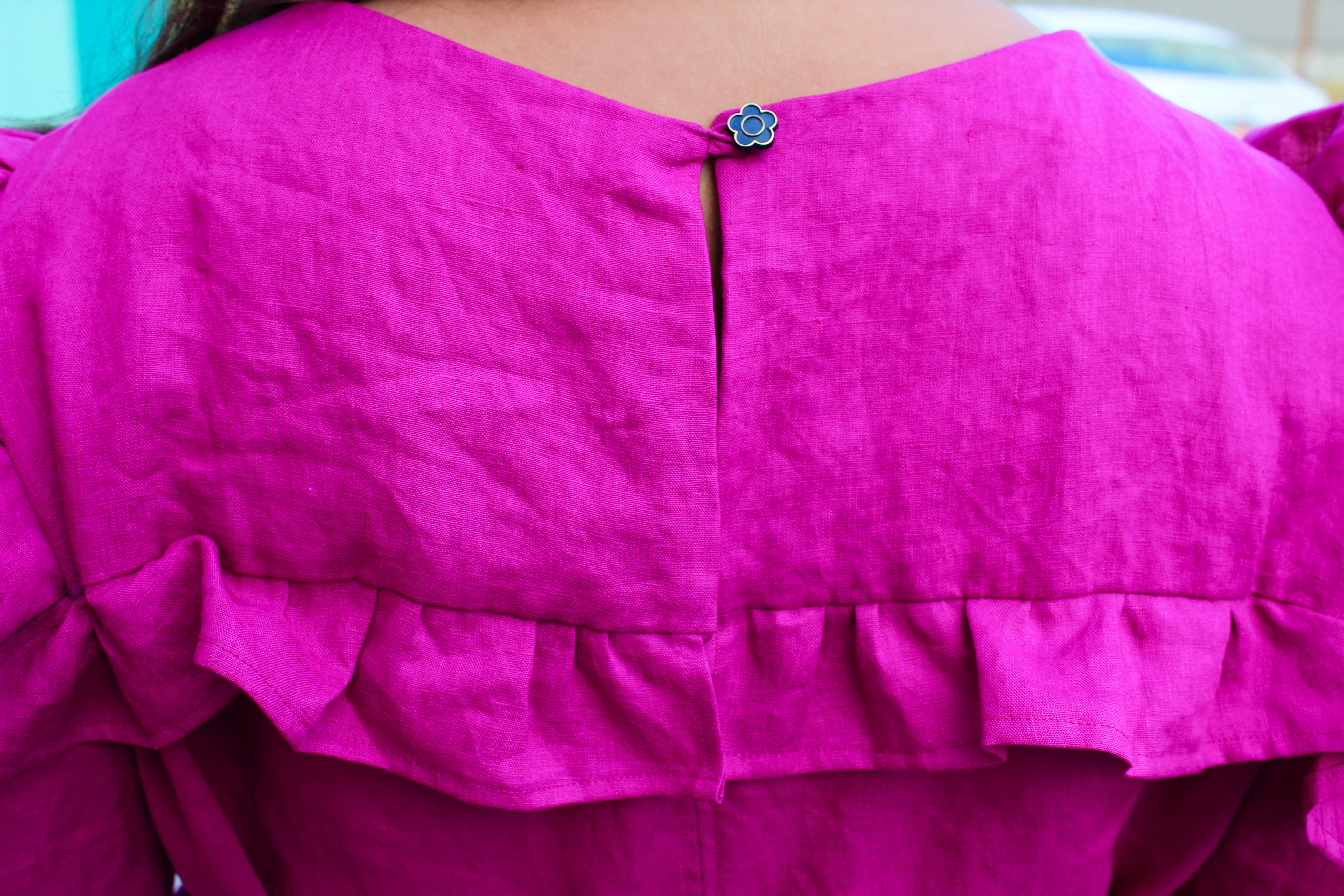 Close up detail of the back closure of Romy's handmade pink dress.  This image shows the metal flower button and loop closure for the back of the dress