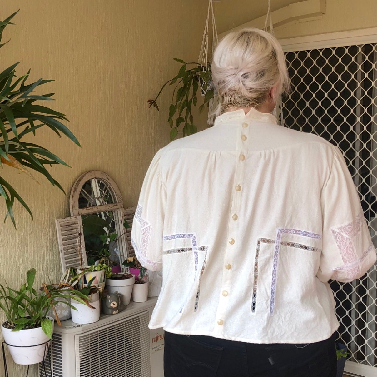 Shannon stands facing away from the camera to show the back details of her Gibson Girl blouse