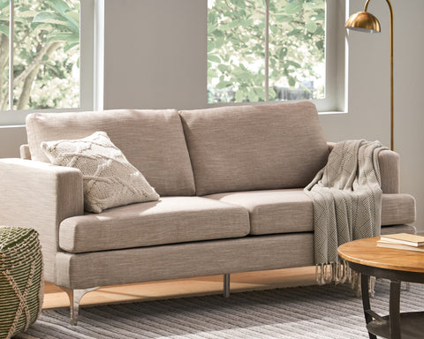 Beige fabric loveseat in front of two windows