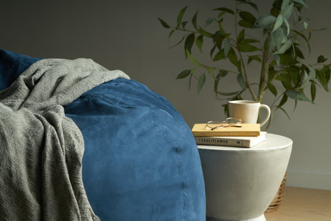 Waldo Navy Blue Microfiber 5 Foot Bean Bag next to a concrete side table