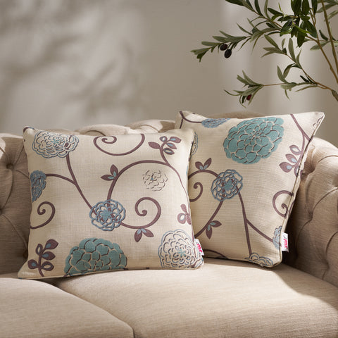 Two floral throw pillows on a beige sofa