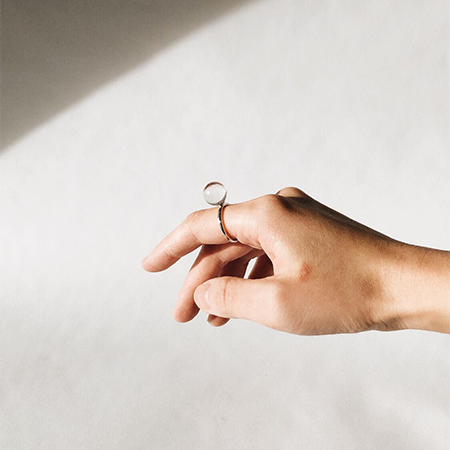 A hand floating in the air wearing a crystal rock big sphere ring in sterling silver