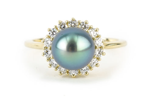 A gold ring with a huge blue-green pearl surrounded by little white diamonds