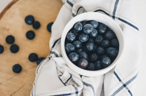 Blueberries in bowl on wood table with white cloth 
