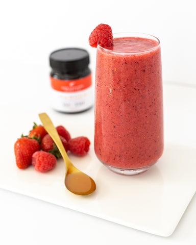 Healthy Red Smoothie on table with fresh berries and Manuka honey