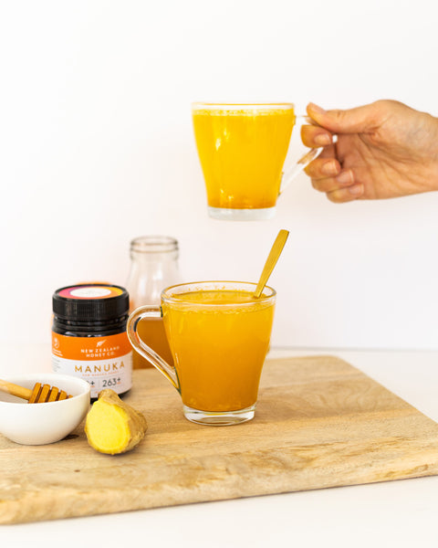 A hand holding a cup of the finished immunity drink with Manuka Honey