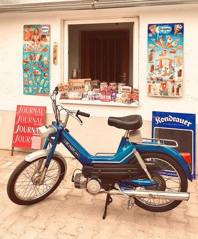 Here you can see a recreated backdrop of an old kiosk with the old ice cream bars from Schöller and Langnese. In the foreground there is a parked Puch maxi moped.