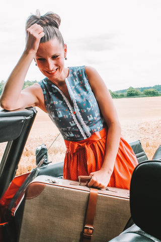 Dirndl München Shooting Drindl Shooting mit alten Koffer und Landschaftsaufnahme. Eine Frau im Dirndl mit einerm Mercedes Cabrio in ro.