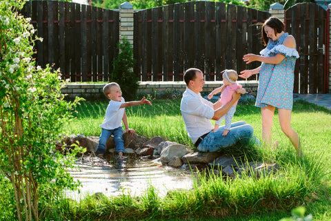 Happy family playing in a garden with pond