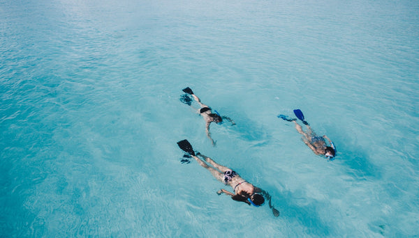 Family of three goes snorkeling in crystal clear waters