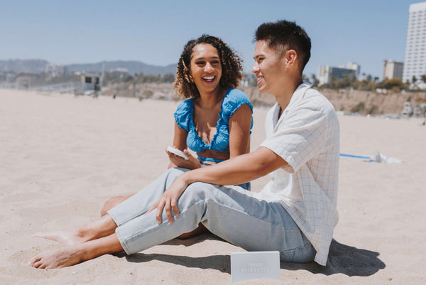 How To Be a Better Lover: Couple on a date and sitting together at the beach.