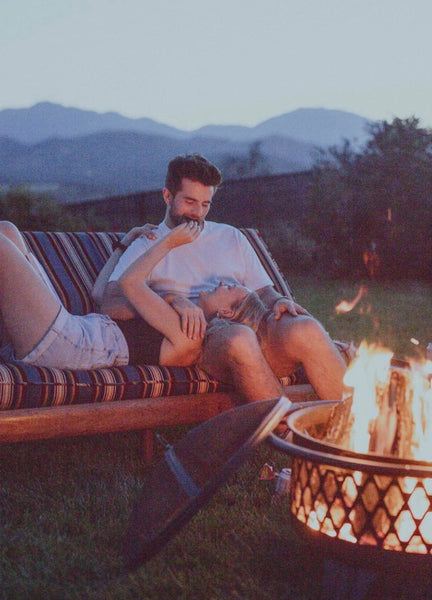 How To Be a Better Lover: Couple lounging around outdoors in front of bonfire.