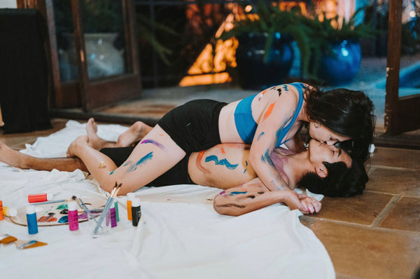 Couple sharing a kiss on the floor as they experiment with paint 