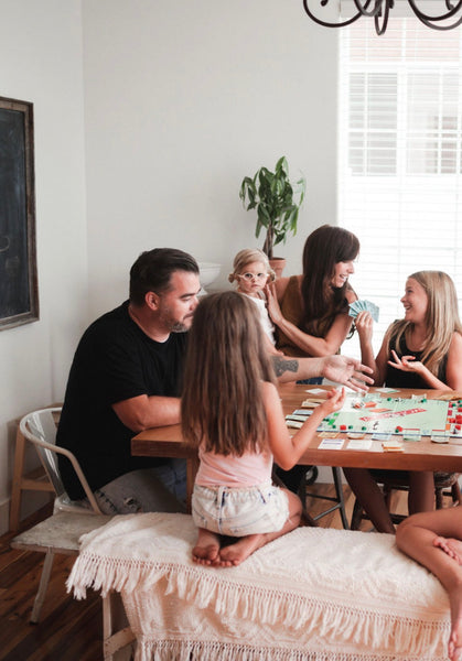 29 Fun Activities To Do At Home With The Kids. Family playing board games in their living room.
