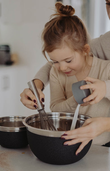 29 Fun Activities To Do At Home With The Kids. Little girl trying out a new recipe with her mother.