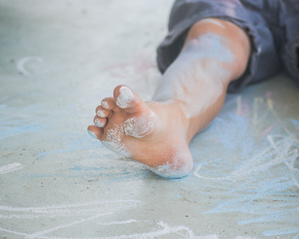 Close-up shot of a kid's toes with blue chalk