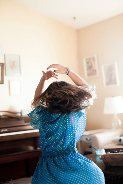 Little girl wearing a blue polka dot dress dancing and twirling around in her room