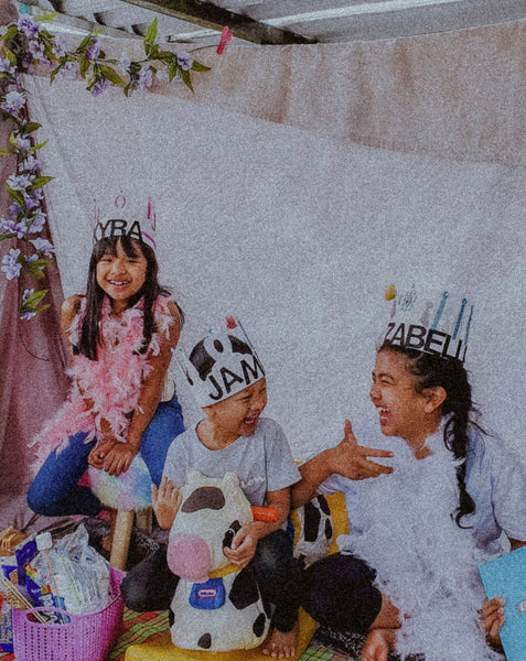 Three kids laughing together and putting on a play with costumes on 
