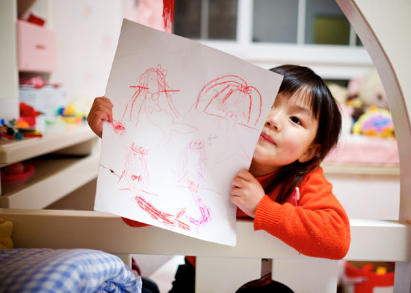 Little girl holding up her art, a great activity for kids who love to create