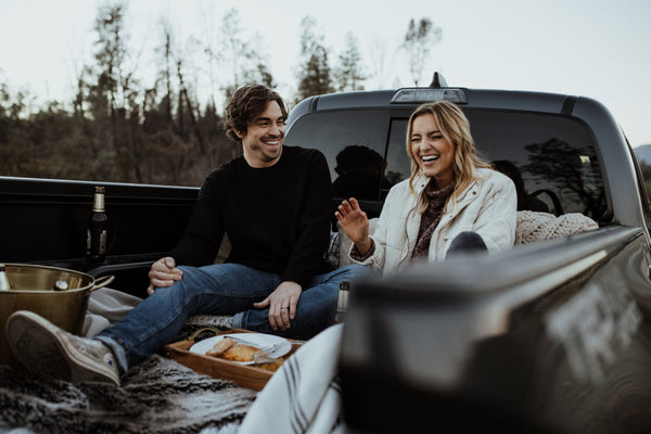 5 date ideas to celebrate national couple’s day: Couple sharing laughs during their casual date on back of pick up truck