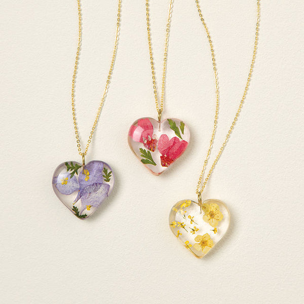 Three heart necklaces with different kinds of flowers inside them