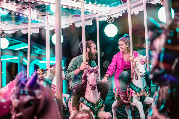 55 Cheap Date Ideas That Are Fun And Create Connection. Couple smiling at each other as they ride on a carousel.