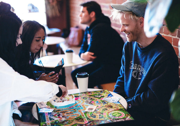 55 Cheap Date Ideas That Are Fun And Create Connection. Group of friends playing board games at a cafe.