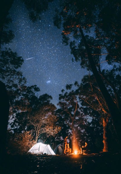 55 Cheap Date Ideas That Are Fun And Create Connection. Couple stargazing inside tent with bonfire and night sky full of stars.