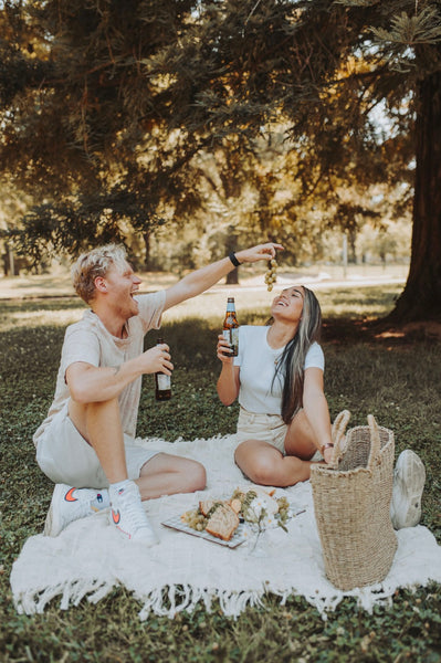 7 Ways to Rekindle Your Relationship's Spark: Guy feeding girl grapes as they enjoy a picnic in the park