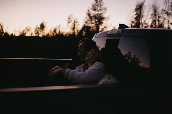 Conversation Starters For Married Couples: Couple sitting and sharing laughs on the back of pick-up truck