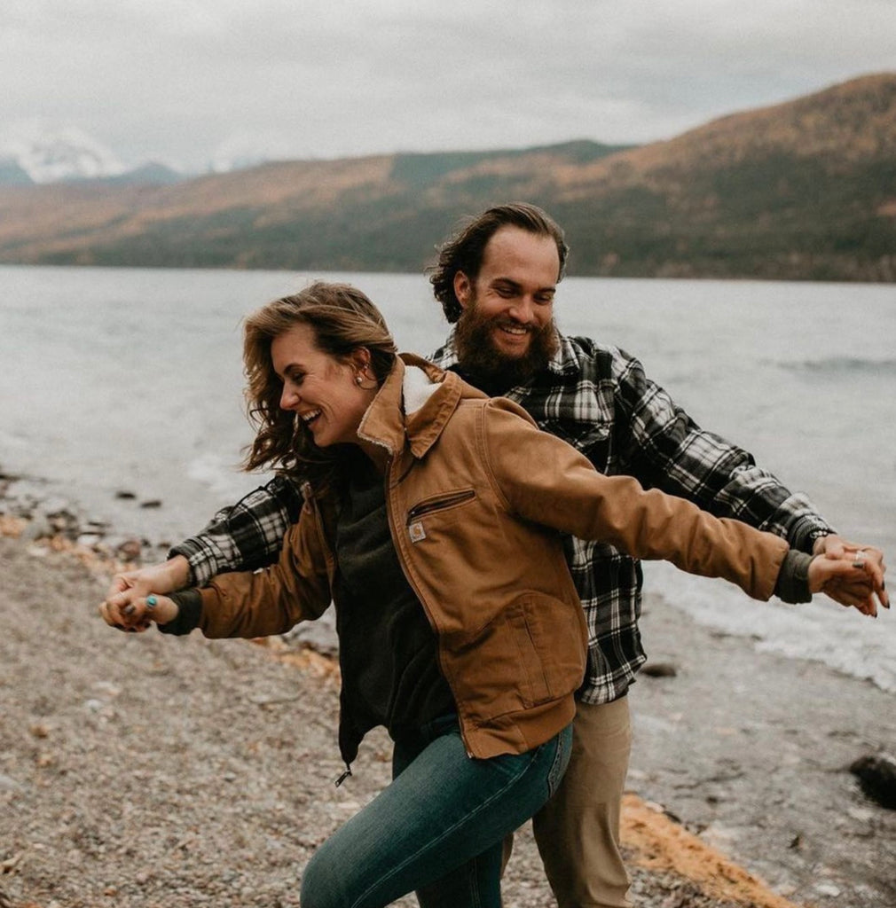 Reignite the spark in your relationship with weekly date nights. Couple laughing together during their nature hike by the lake.