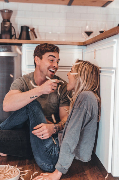 At Home Date Night Ideas: Couple feeding each other and playing with fries